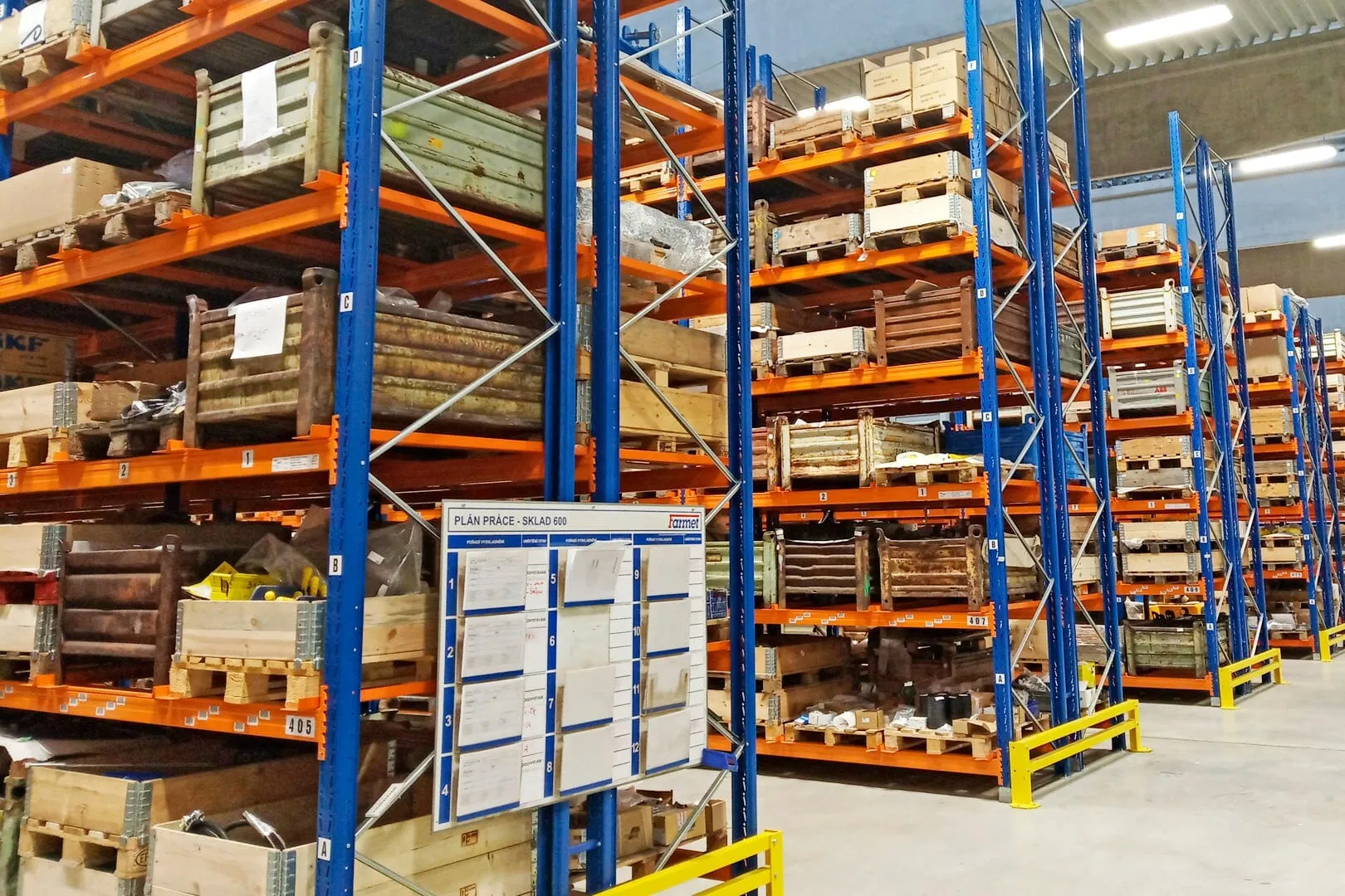 Hohe Regalreihen eines Ersatzteillagers mit Gitterboxen und Holzkisten